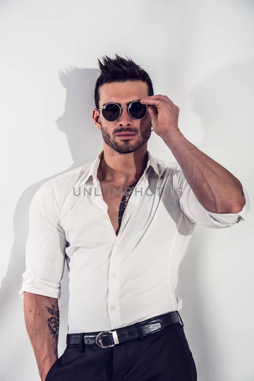 Photo of a muscular and attractive man in a white shirt and black pants by artofphoto
