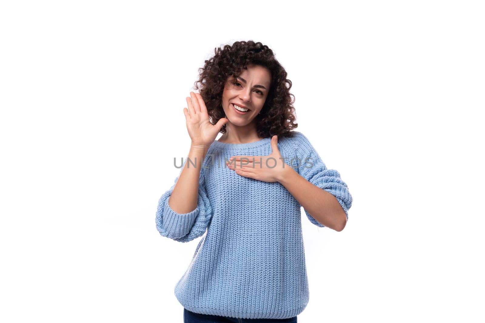 young well-groomed woman with curled hair is dressed in a blue sweater by TRMK