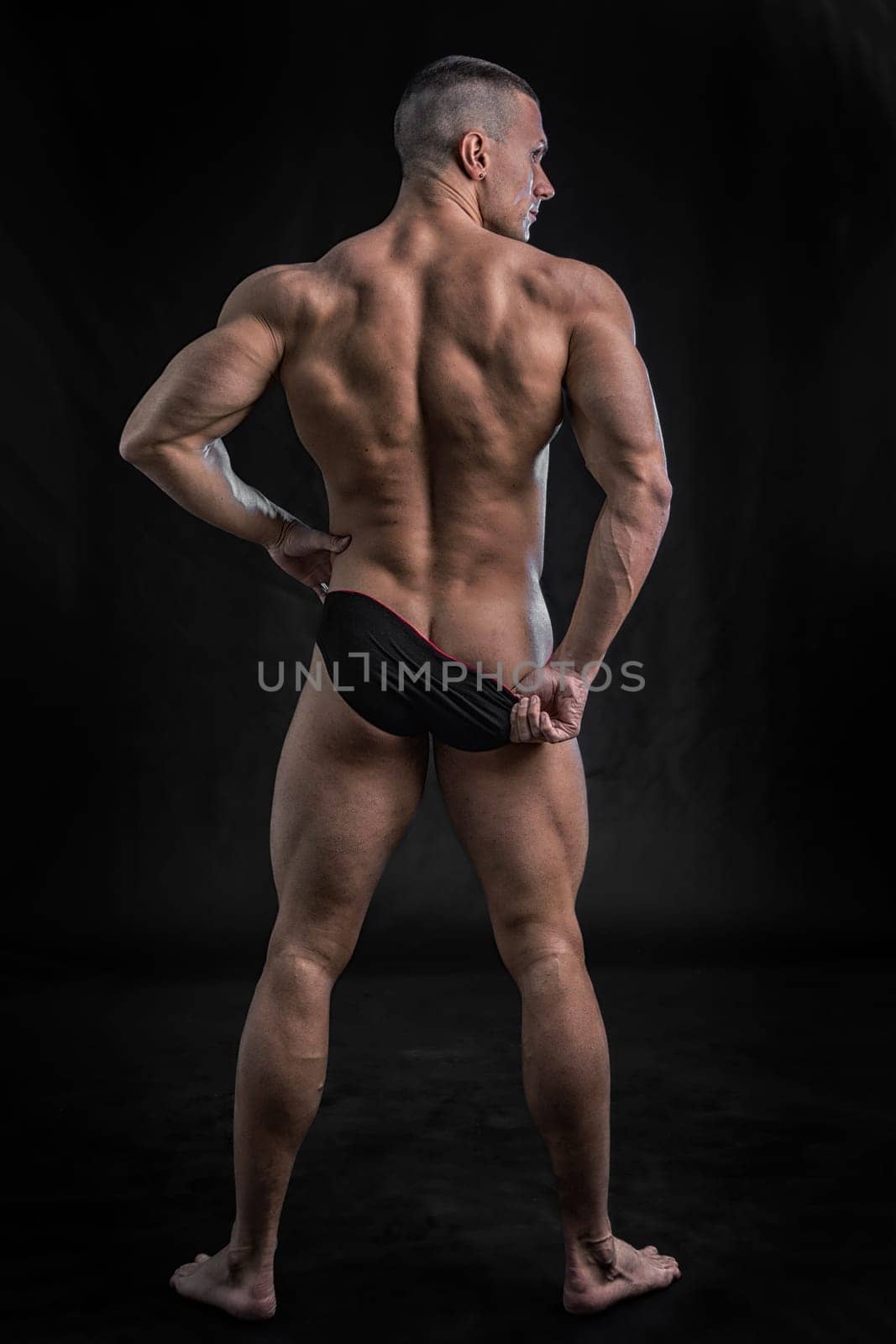 Muscular man pulling down underwear to show his butt, in studio shot