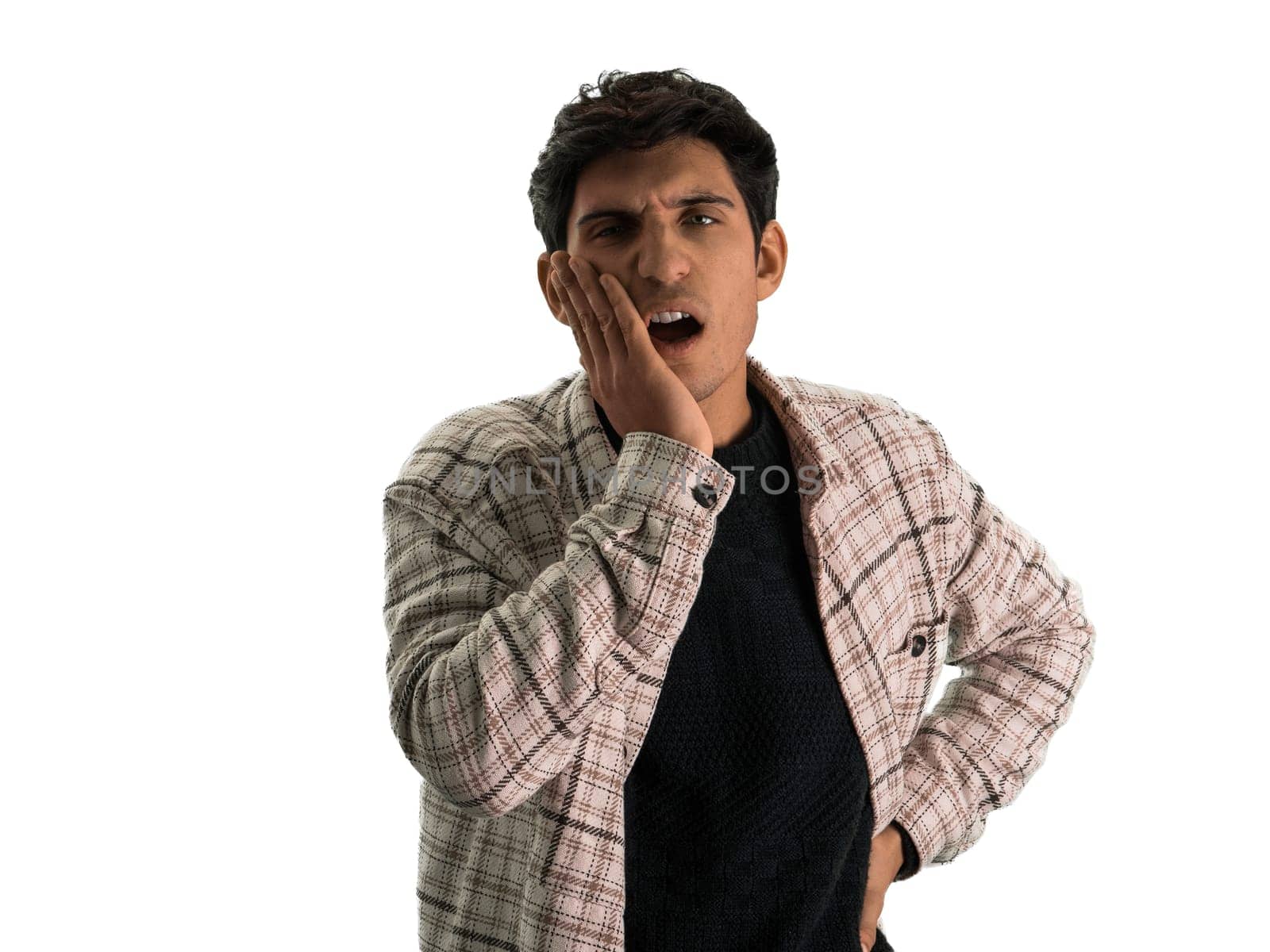 Handsome young man suffering from toothache, looking at camera, touching his face, isolated on white
