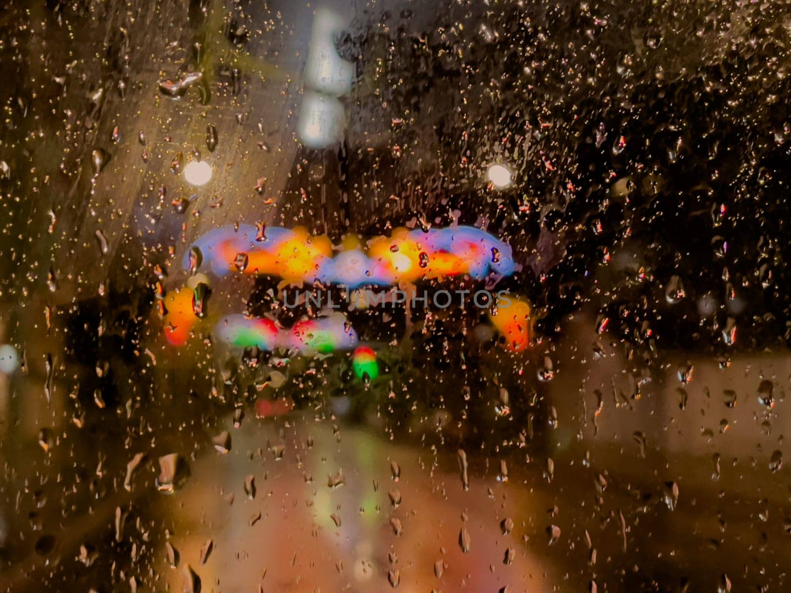 Rain bokeh road lights. Abstract shot of evening city traffic bokeh. Multicolored lights of the evening city and passing cars through a wet rainy window. by Matiunina
