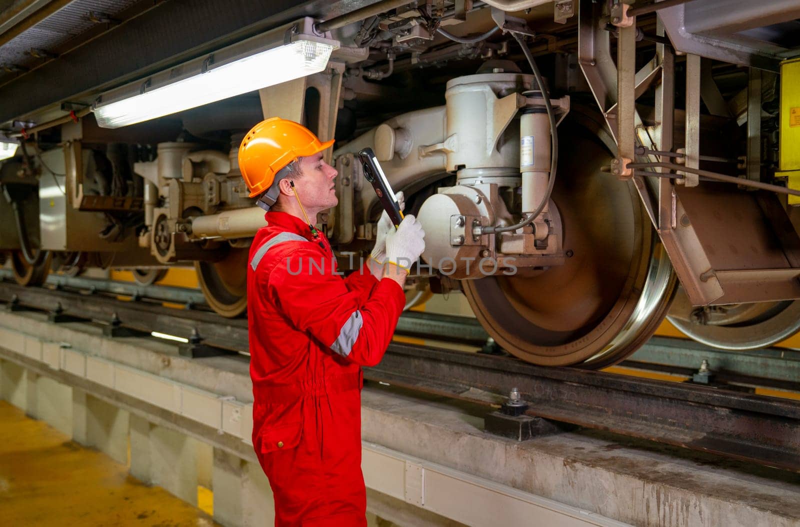 Professional technician worker hold light tube to check and maintenance part of train in electrical or metro train factory.