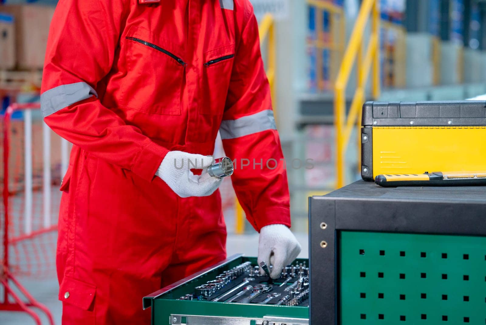 Side view of hands of technician worker hold screw nut and check tools or equipment in the cabinet in front of railroad tracks of electrical or sky train in factory workplace.