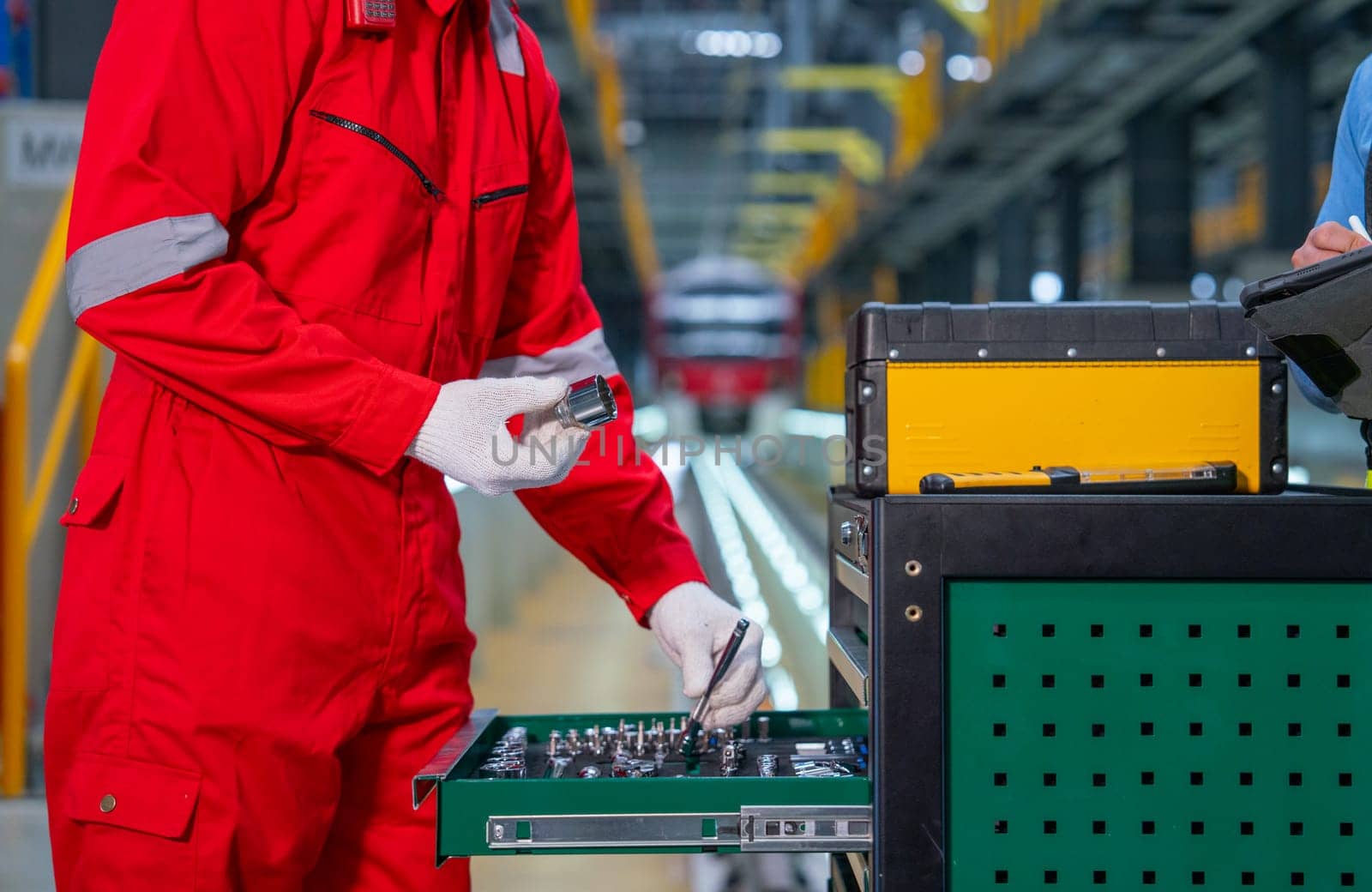 Close up hands of technician worker hold screw nut and check tools or equipment in the cabinet in front of railroad tracks of electrical or sky train in factory workplace.