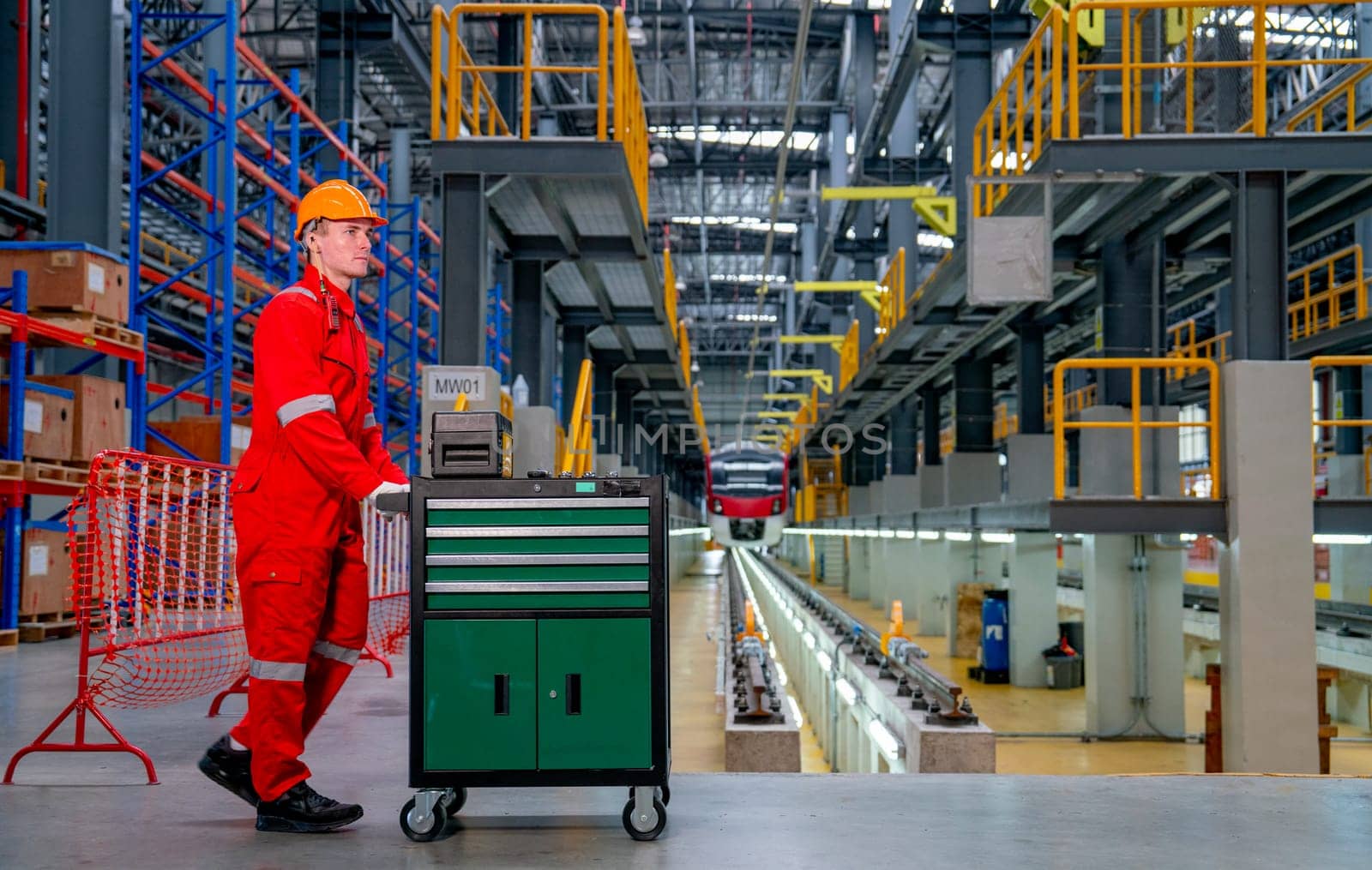 Professional technician worker push cart or cabinet of tools and equipment in front of rail track in electrical or sky train factory workplace.