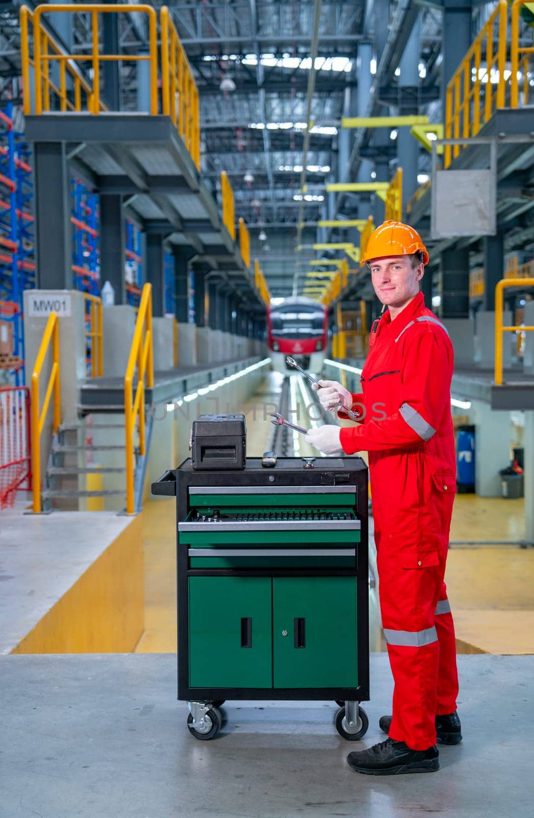 Vertical image of professional technician worker with safety uniform check tools and equipment in the cabinet with look at camera in electrical or sky train factory.