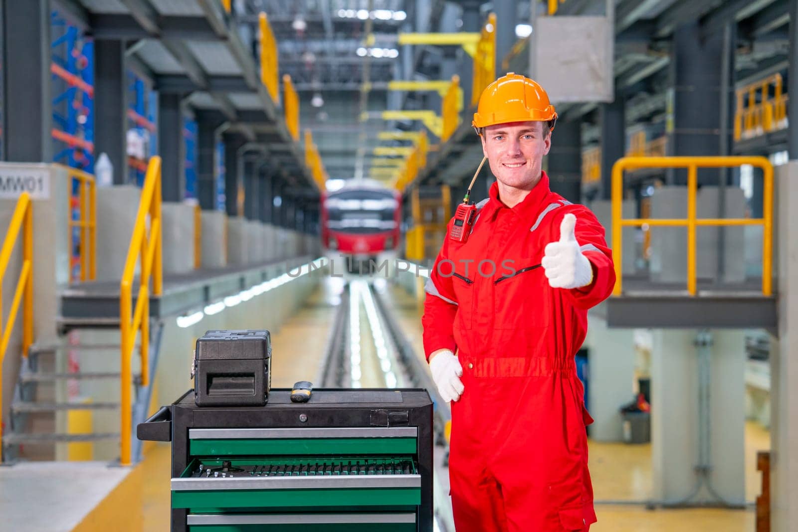 Professional technician worker stand with thumbs up and look at camera with smiling in electrical or sky train factory workplace.