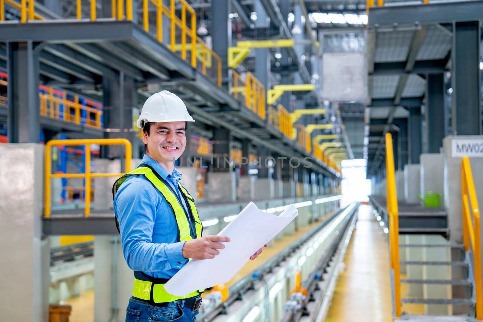 Portrait of professional engineer hold construction chart or plan and look at camera with smiling in electrical or sky train factory workplace.