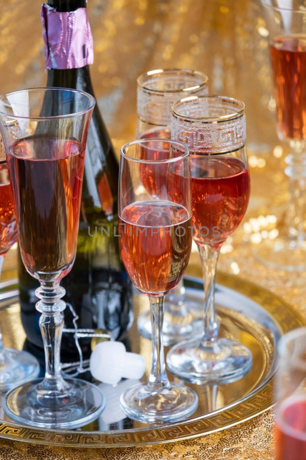 glasses of rose champagne on sparkling golden cloth by Desperada