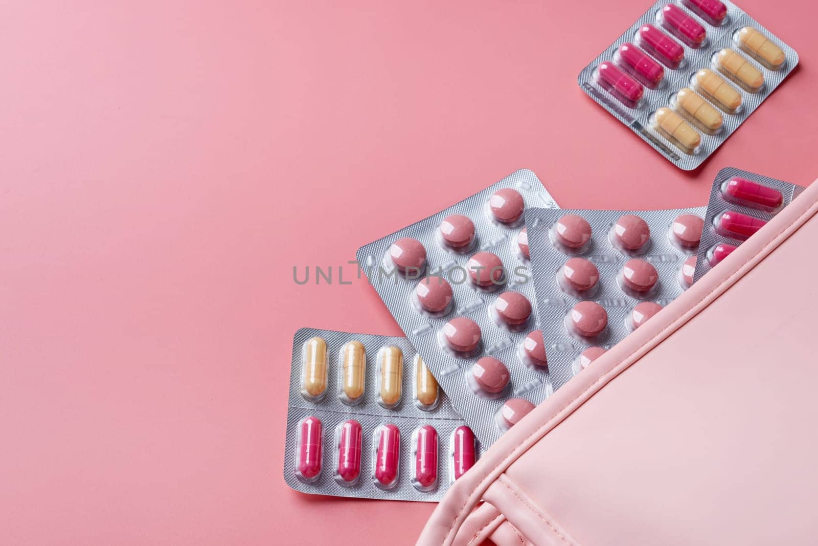 Flat lay composition with pink female cosmetic bag blisters on color background. womens health