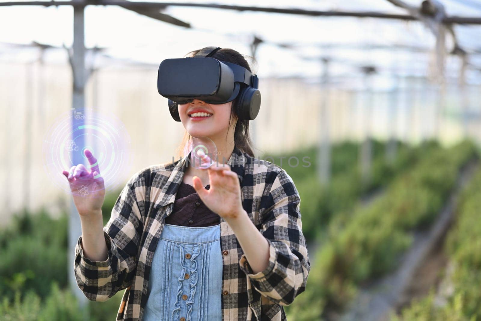 Farmer wearing VR headset for controlling process in greenhouse cultivation. Modern and smart agriculture concept