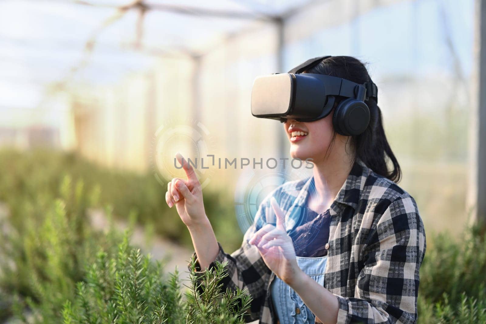 Farmer wearing VR headset for controlling process in greenhouse cultivation. Modern and smart agriculture concept. by prathanchorruangsak