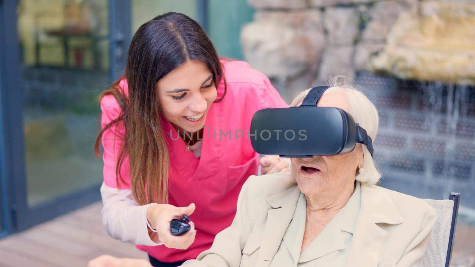 Nurse controlling remotely the vision of a senior woman using virtual reality goggles