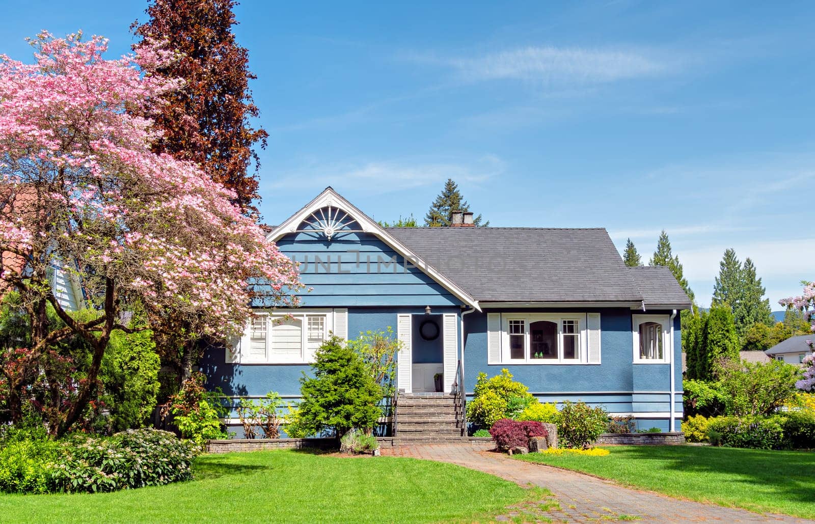 A perfect neighborhood. Neat residential house with green lawn in front on blue sky background