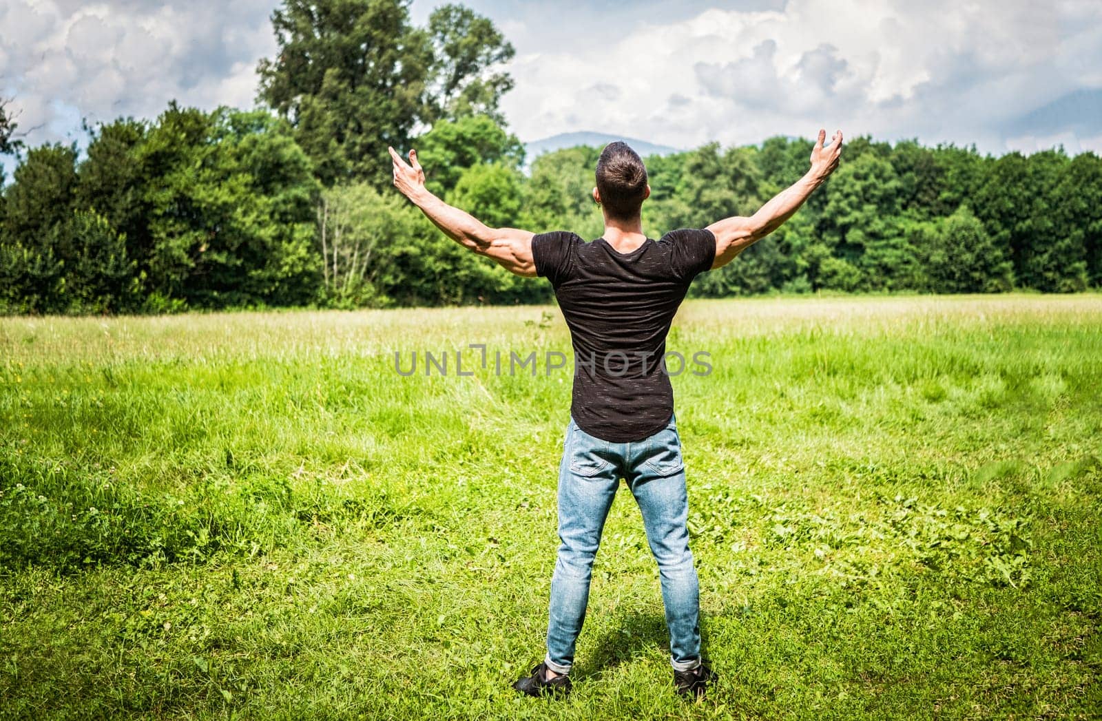 Photo of a man standing with arms outstretched in a beautiful field by artofphoto