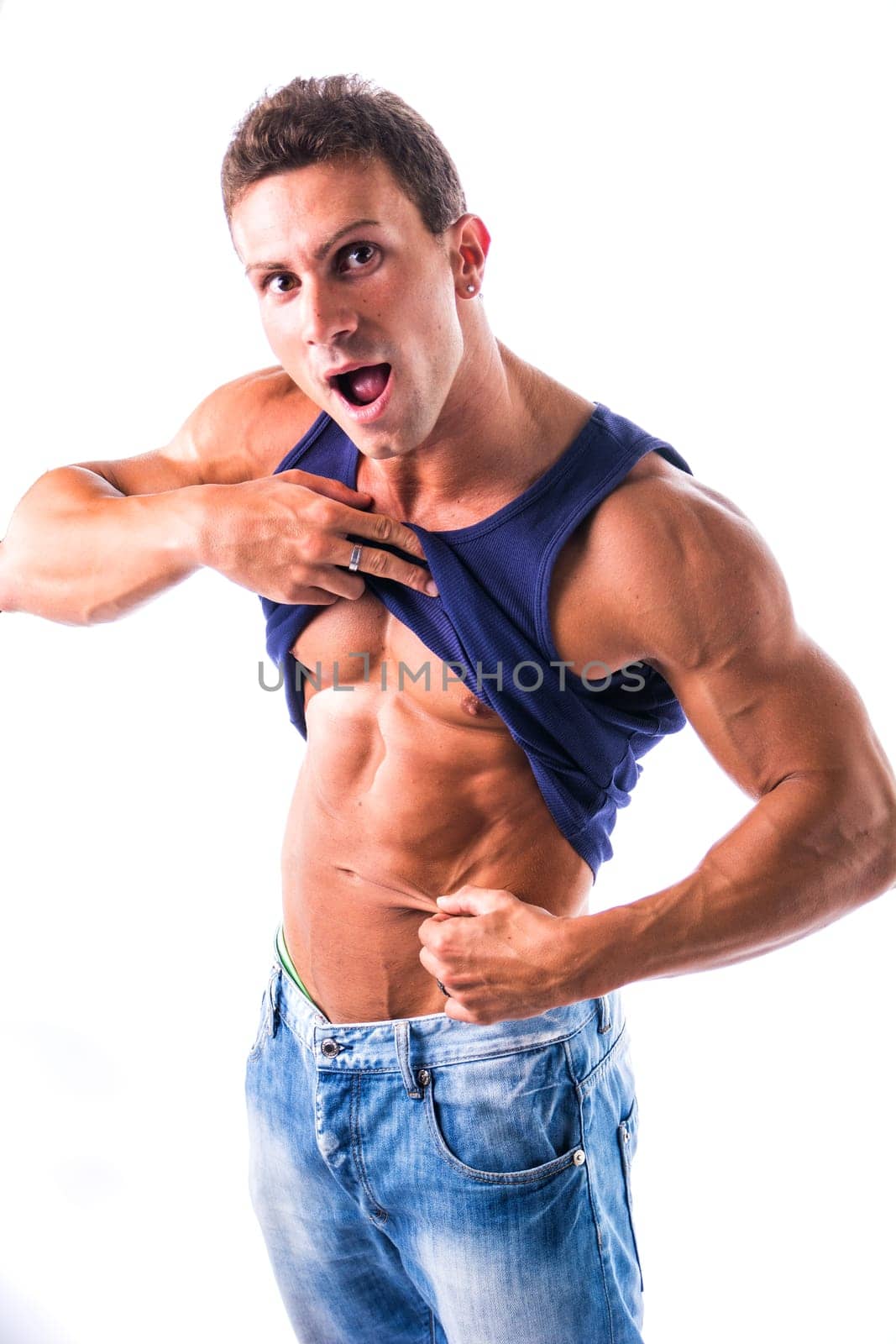 Fit, athletic muscular young man pinching his stomach skin and showing abs in studio shot isolated on white