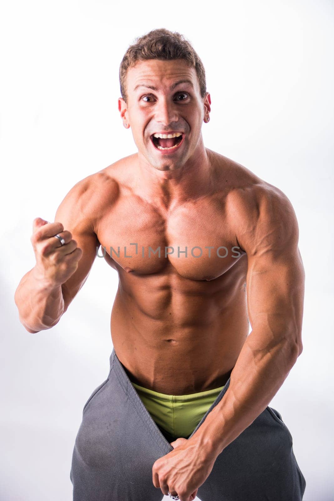 Shirtless Male Bodybuilder Has Lost Weight, Wearing Large Pants, happy expression, in studio