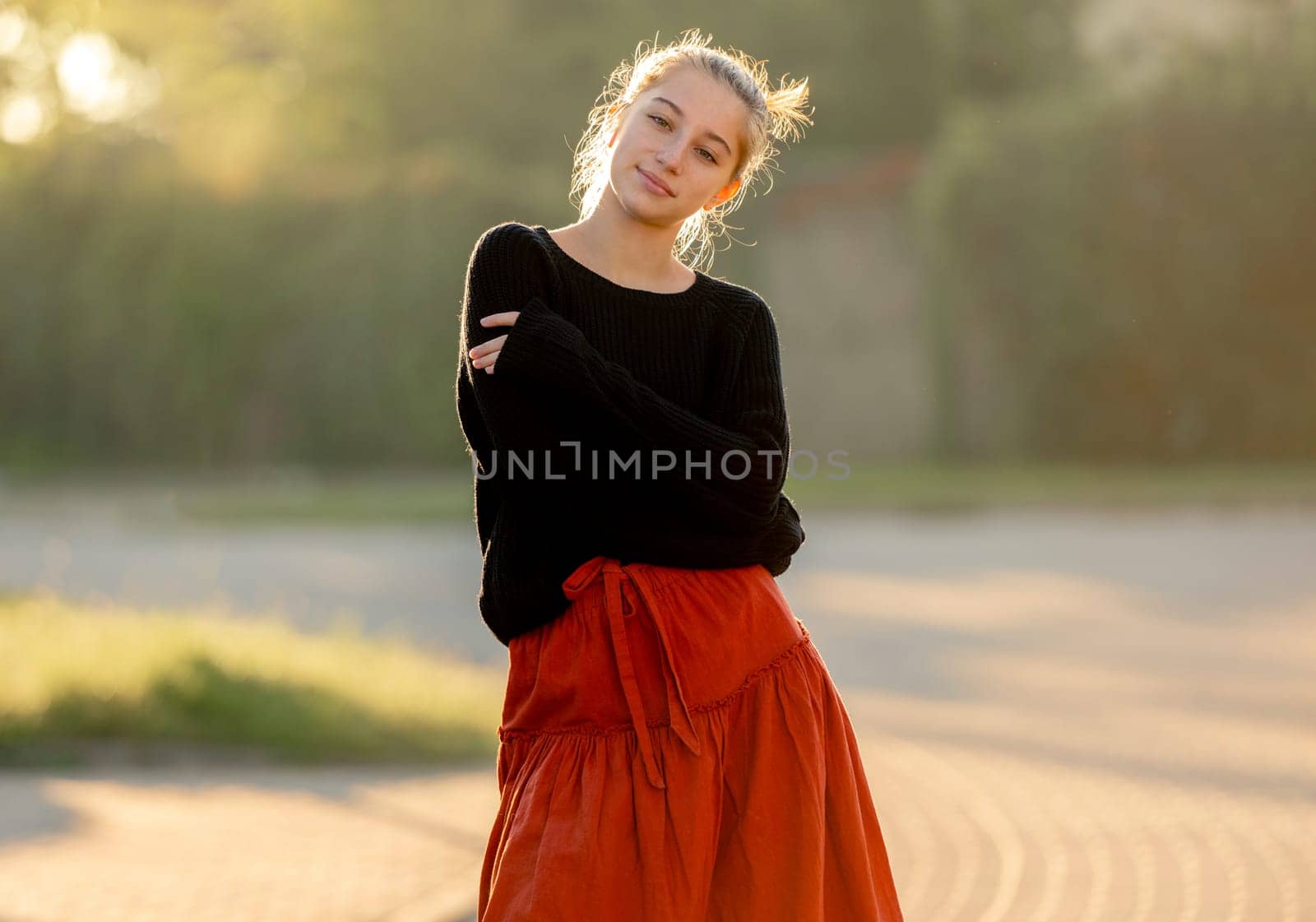 Beautiful teenager girl posing in park outdoors at nature. Pretty teen model in trendy clothes at street portrait