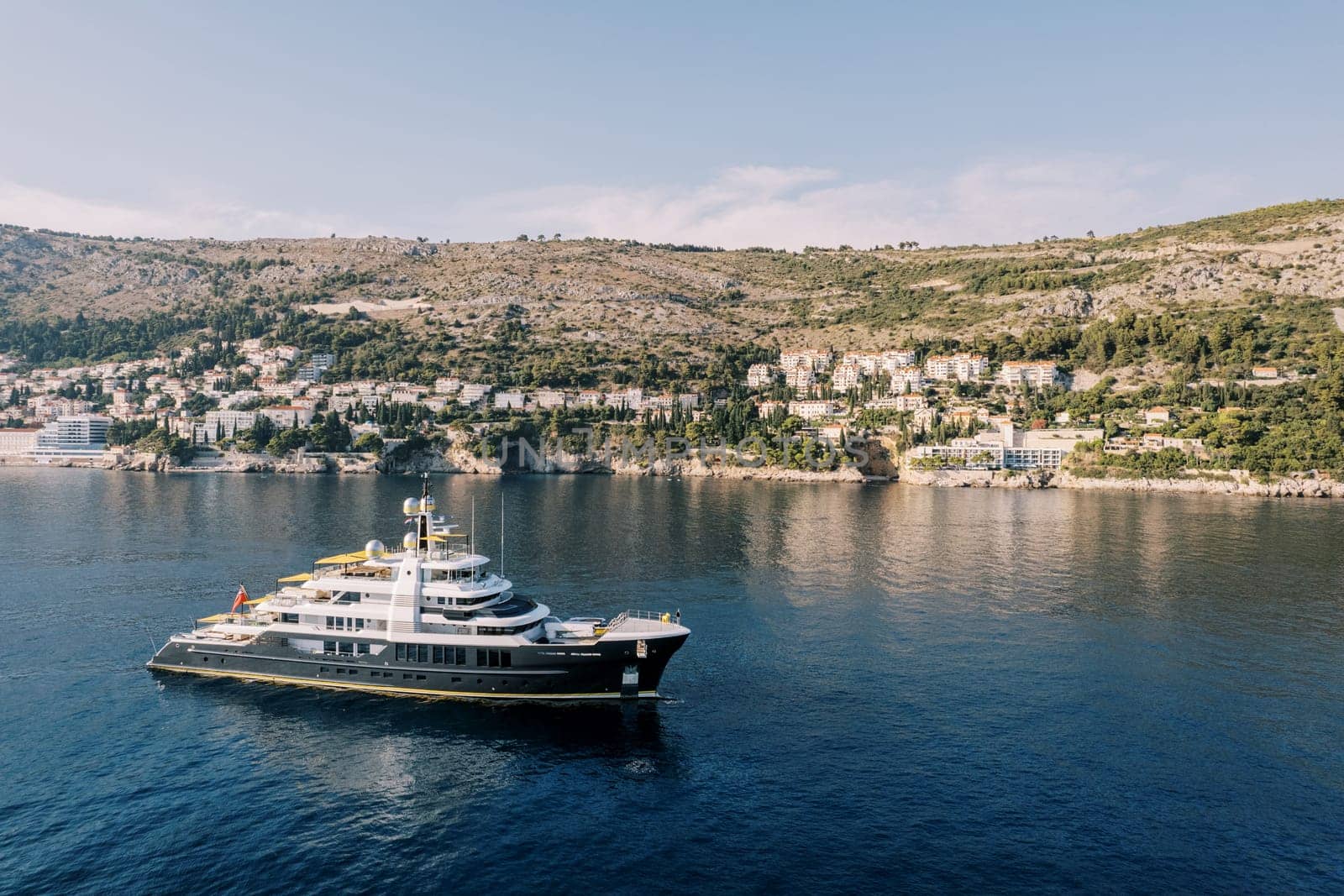 Luxury three-deck yacht sails along the mountainous coastline. High quality photo
