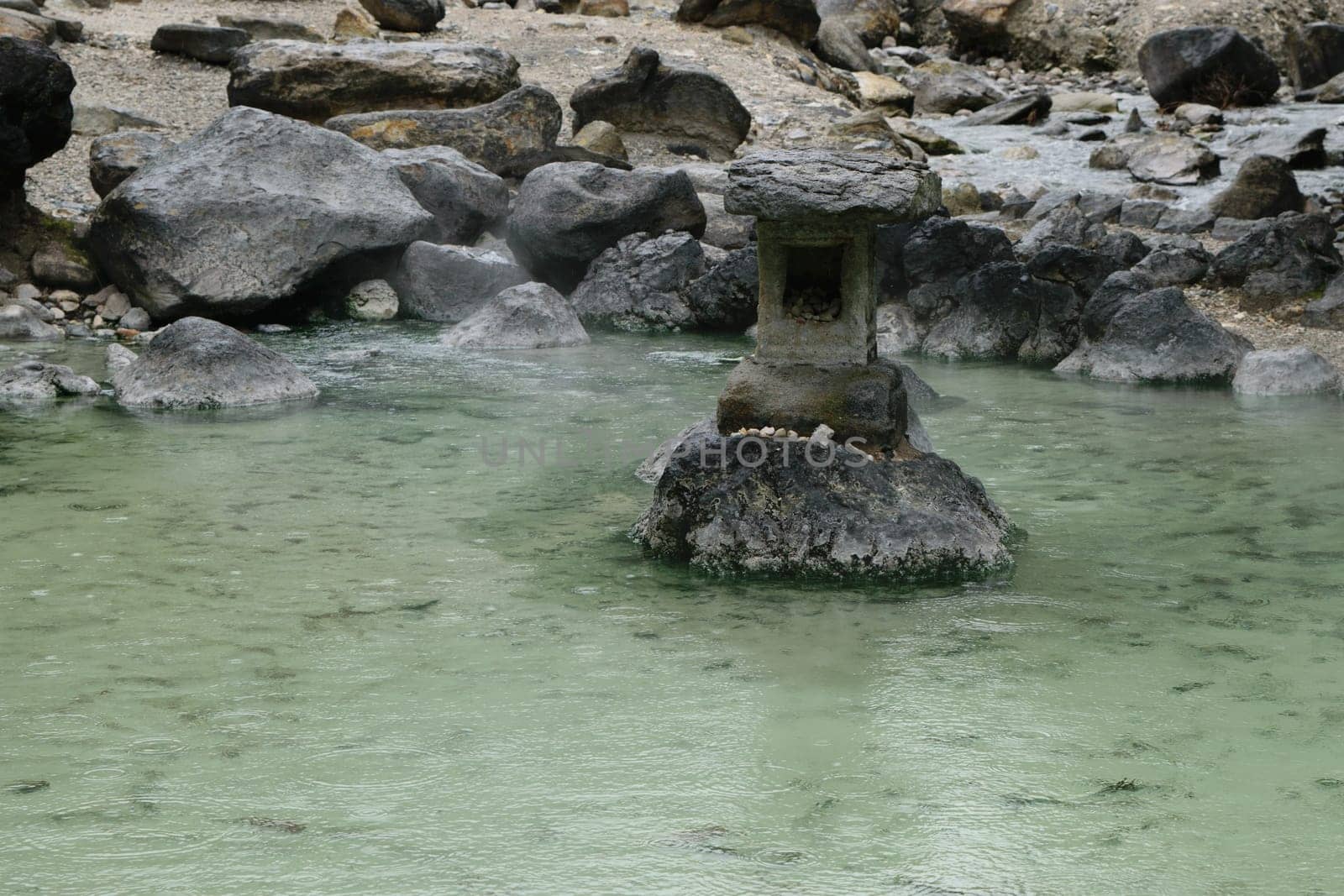 A lantern on a stone surrounded by Japanese onsen water.