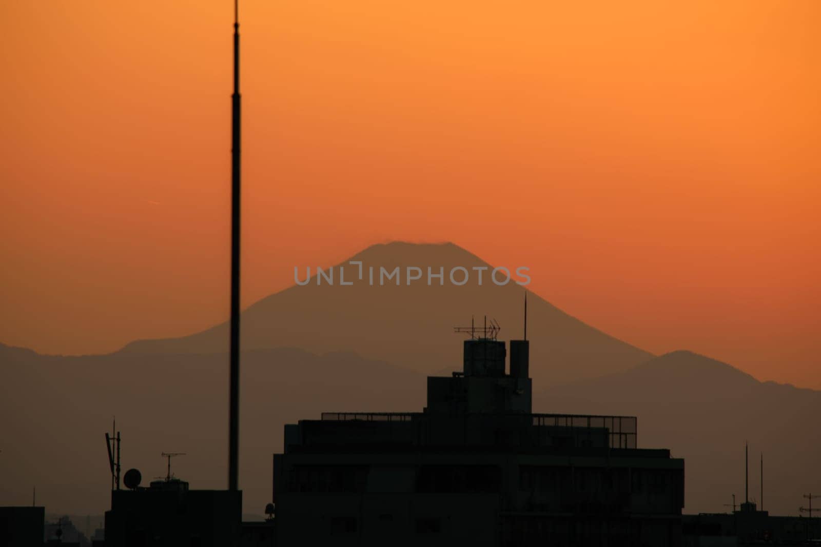 A view of Mt Fuji at sunset with a cityscape in the foreground.
