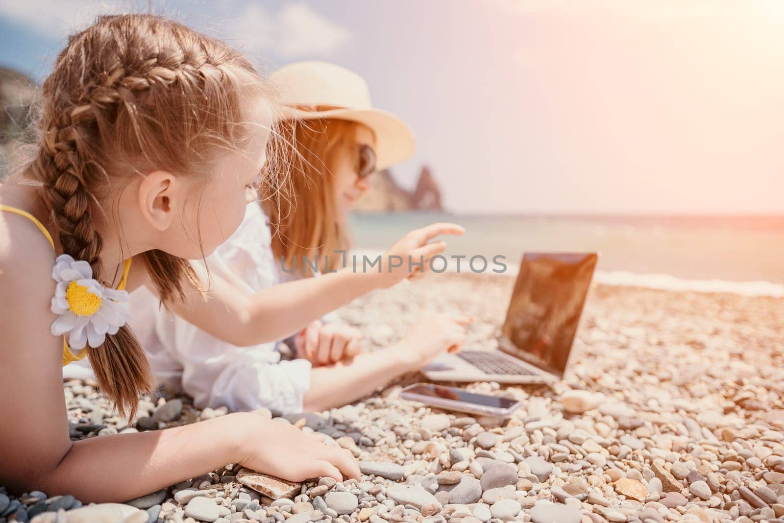 Woman sea laptop. Business woman with daughter, working on laptop by sea. Close up on hands of pretty lady typing on computer outdoors summer day. Freelance, digital nomad, travel and holidays concept by panophotograph