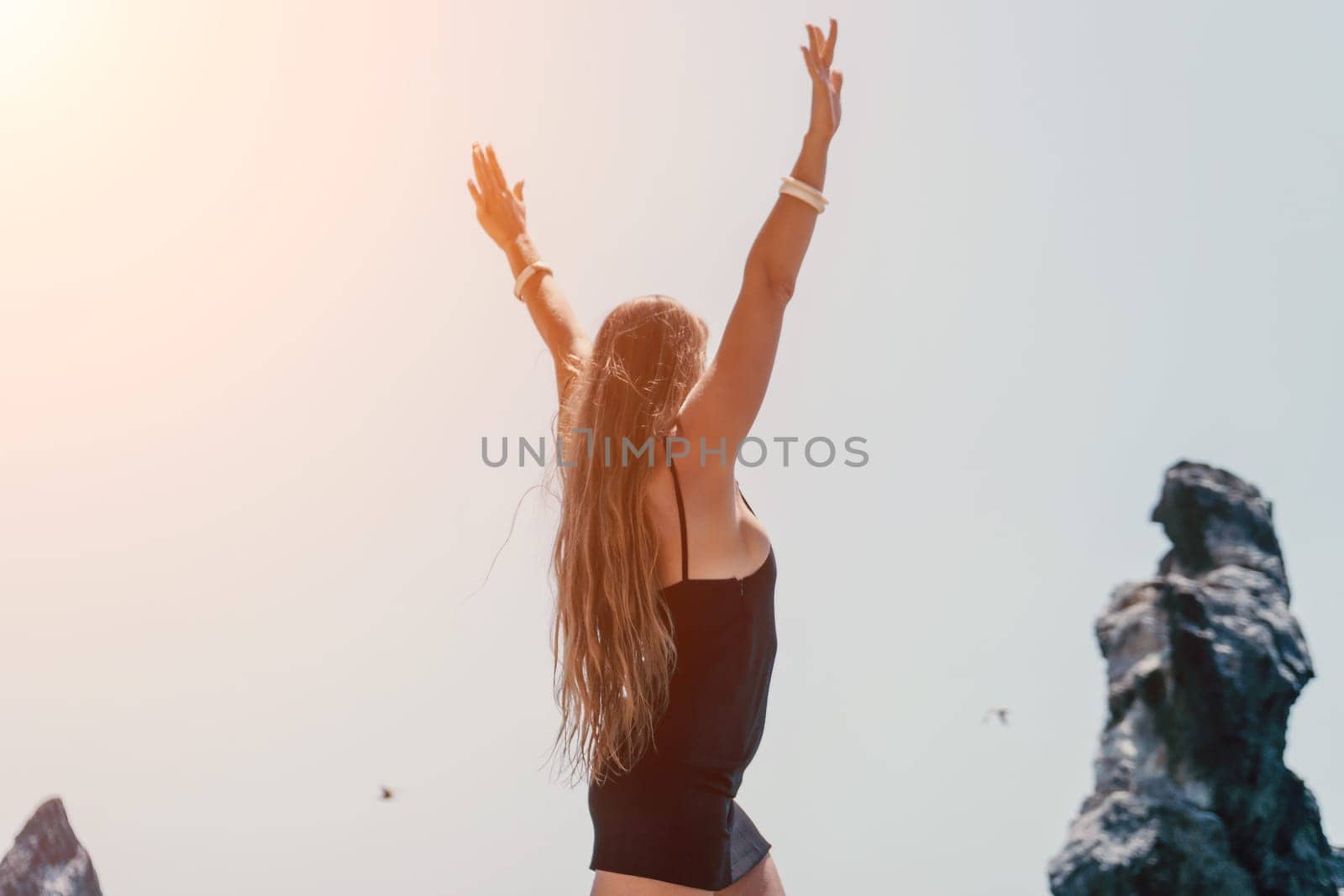 Woman travel sea. Young Happy woman in a long red dress posing on a beach near the sea on background of volcanic rocks, like in Iceland, sharing travel adventure journey