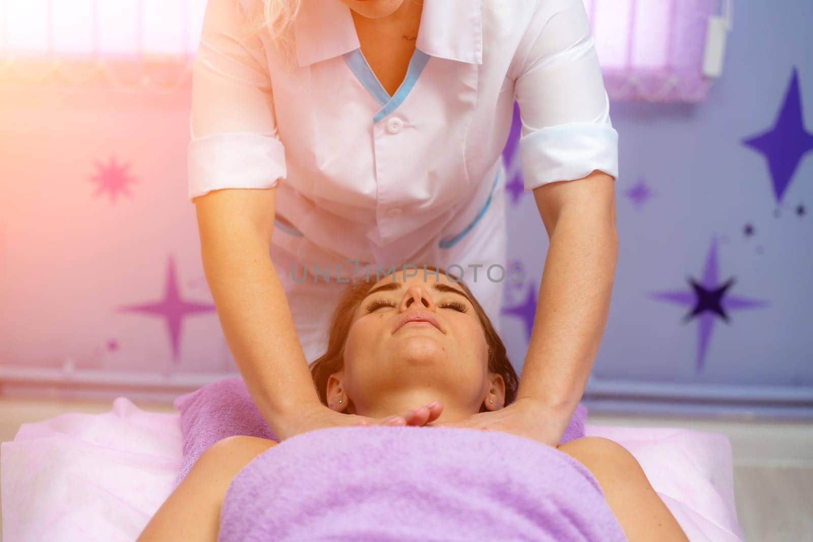 Relaxing massage. European woman getting facial massage in spa salon, side view.