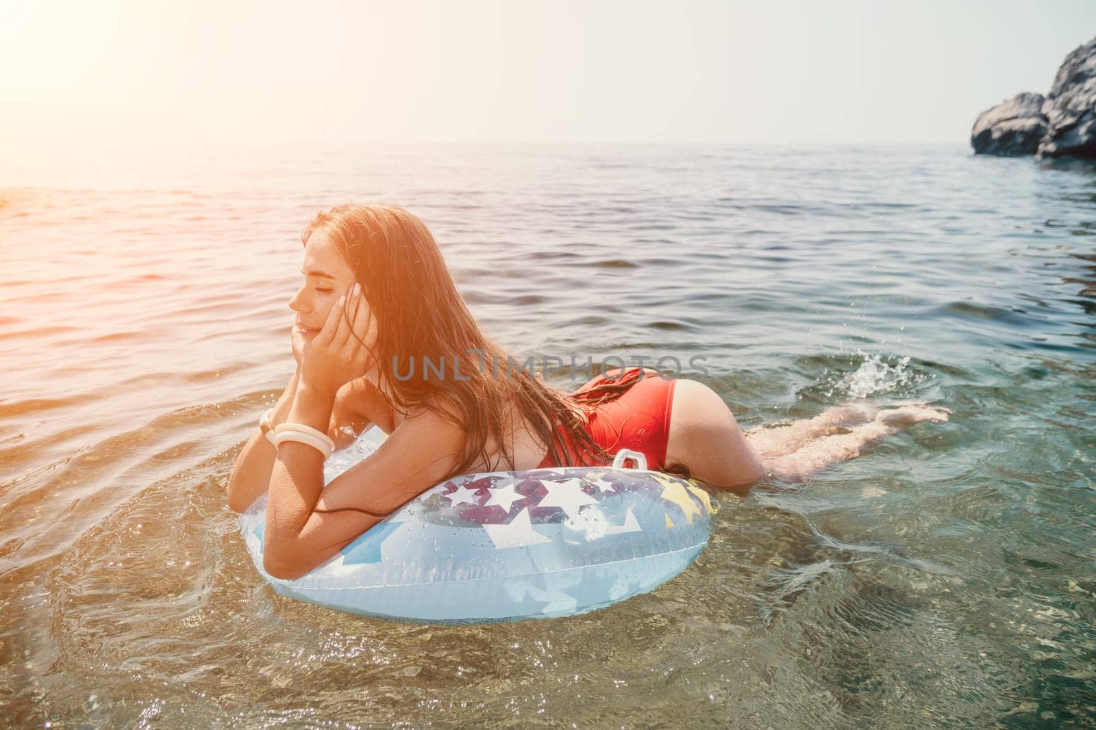 Woman summer sea. Happy woman swimming with inflatable donut on the beach in summer sunny day, surrounded by volcanic mountains. Summer vacation concept