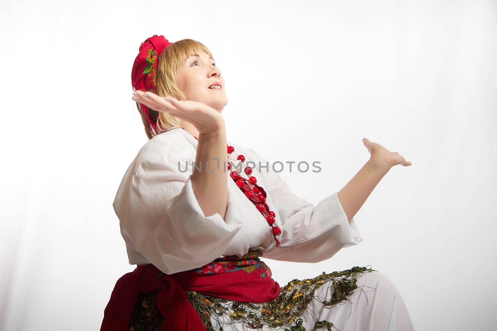 Portrait of a cheerful funny adult mature woman solokha. Female model in clothes of national ethnic Slavic style. A stylized Ukrainian, Belarusian or Russian woman poses in a comic photo shoot by keleny