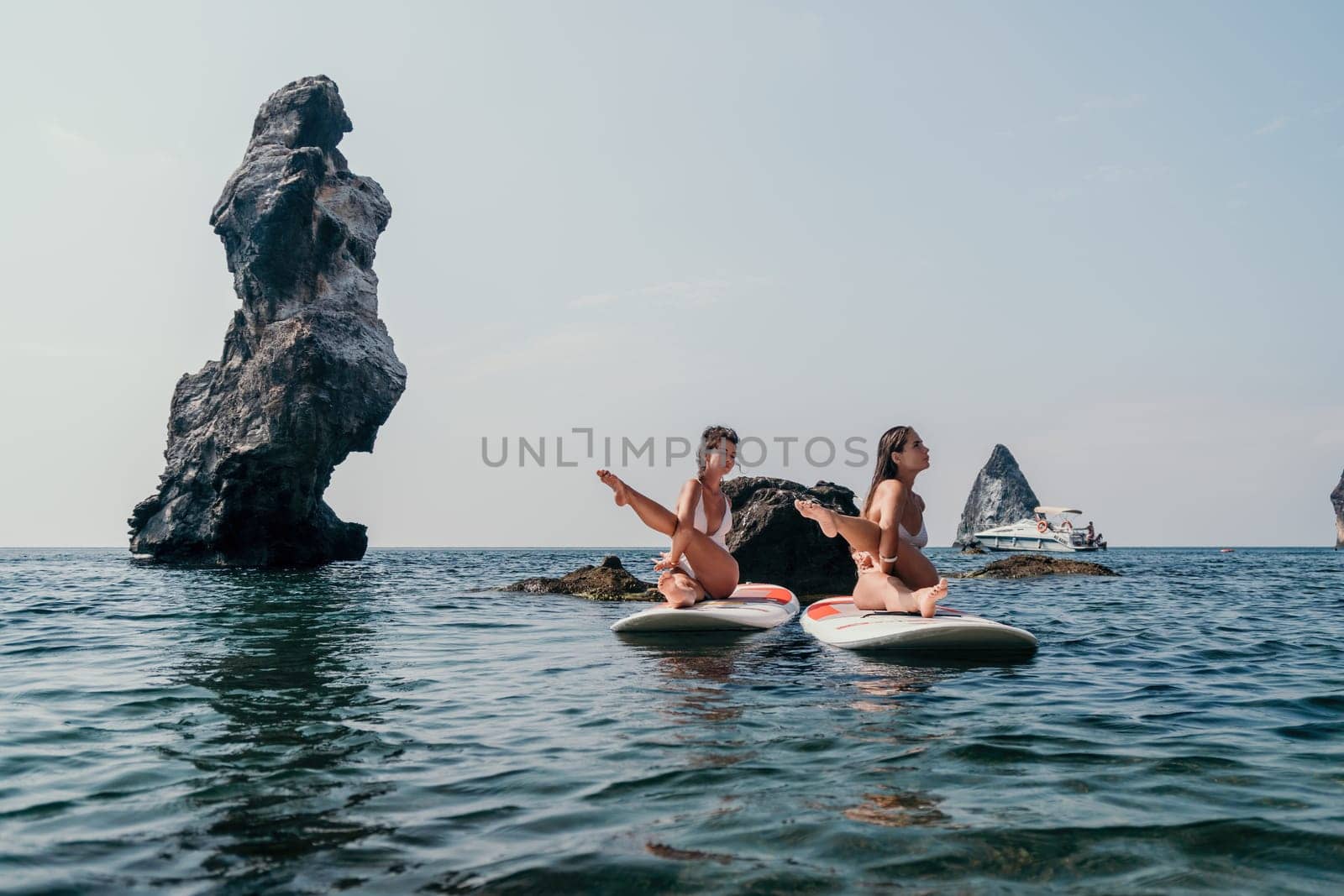 Woman sup yoga. Middle age sporty woman practising yoga pilates on paddle sup surfboard. Female stretching doing workout on sea water. Modern individual hipster outdoor summer sport activity