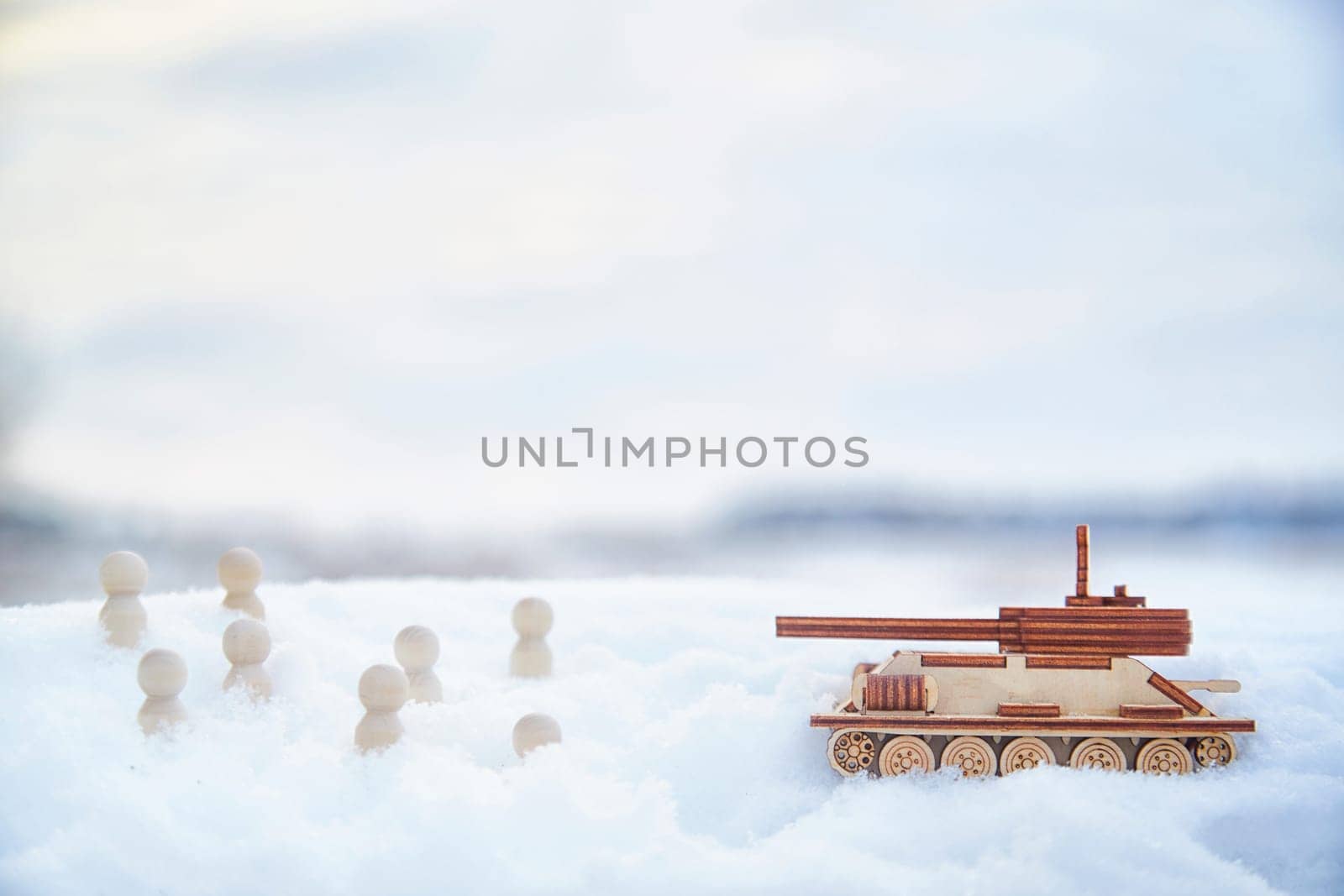 Wooden toy tank and little men in the snow. Russia and Ukraine are at war in winter. Encirclement, retreat, attack, victory