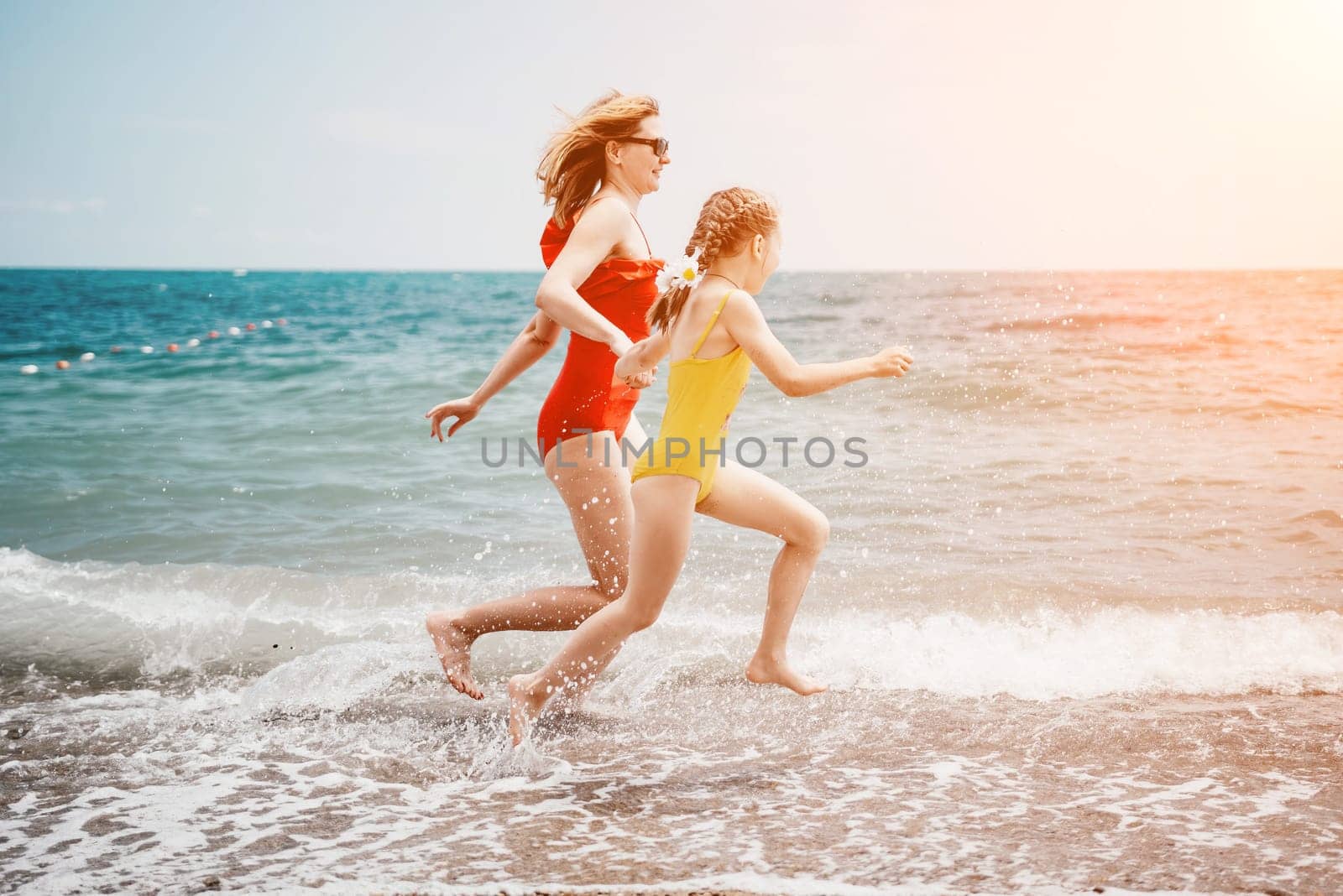 Happy loving family mother and daughter having fun together on the beach. Mum playing with her kid in holiday vacation next to the ocean - Family lifestyle and love concept.