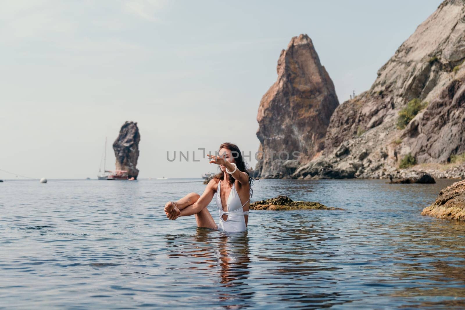 Woman sea fitness. Happy woman in a white bikini performing pilates in the sea on the beach. Female fitness yoga routine concept. Healthy lifestyle. by panophotograph