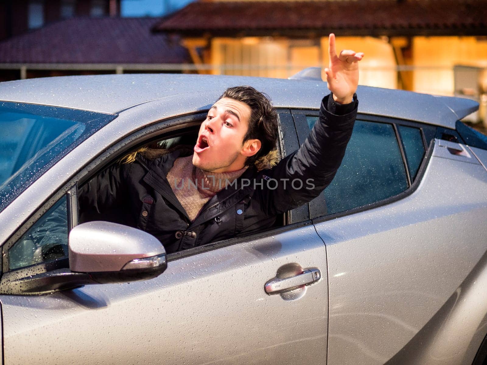 Photo of a man driving a car with his hand raised in the air by artofphoto