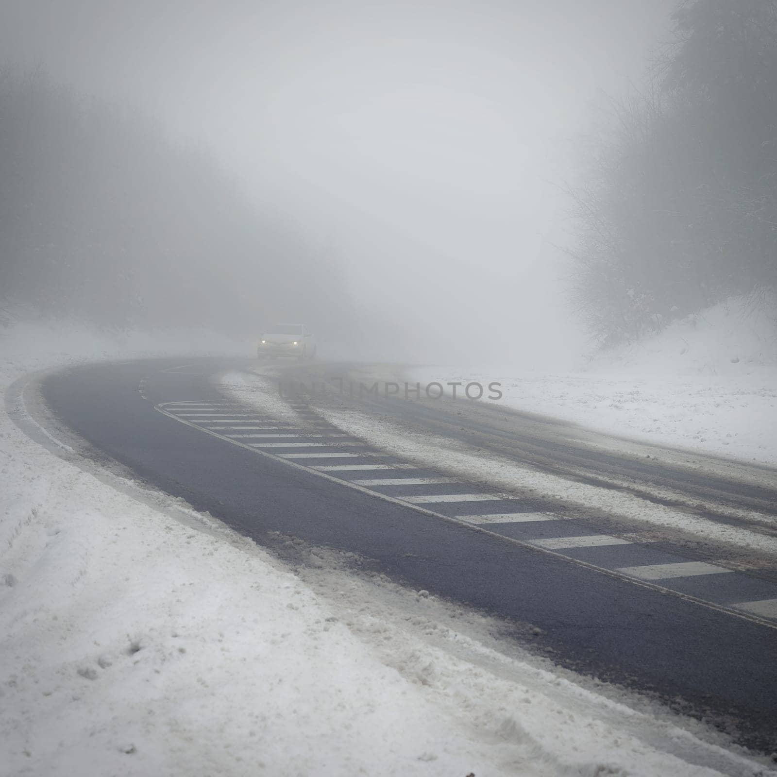 Bad weather driving - foggy hazy country road. Motorway - road traffic. Winter time. Autumn - fall.  Snow and frost on the road in winter.