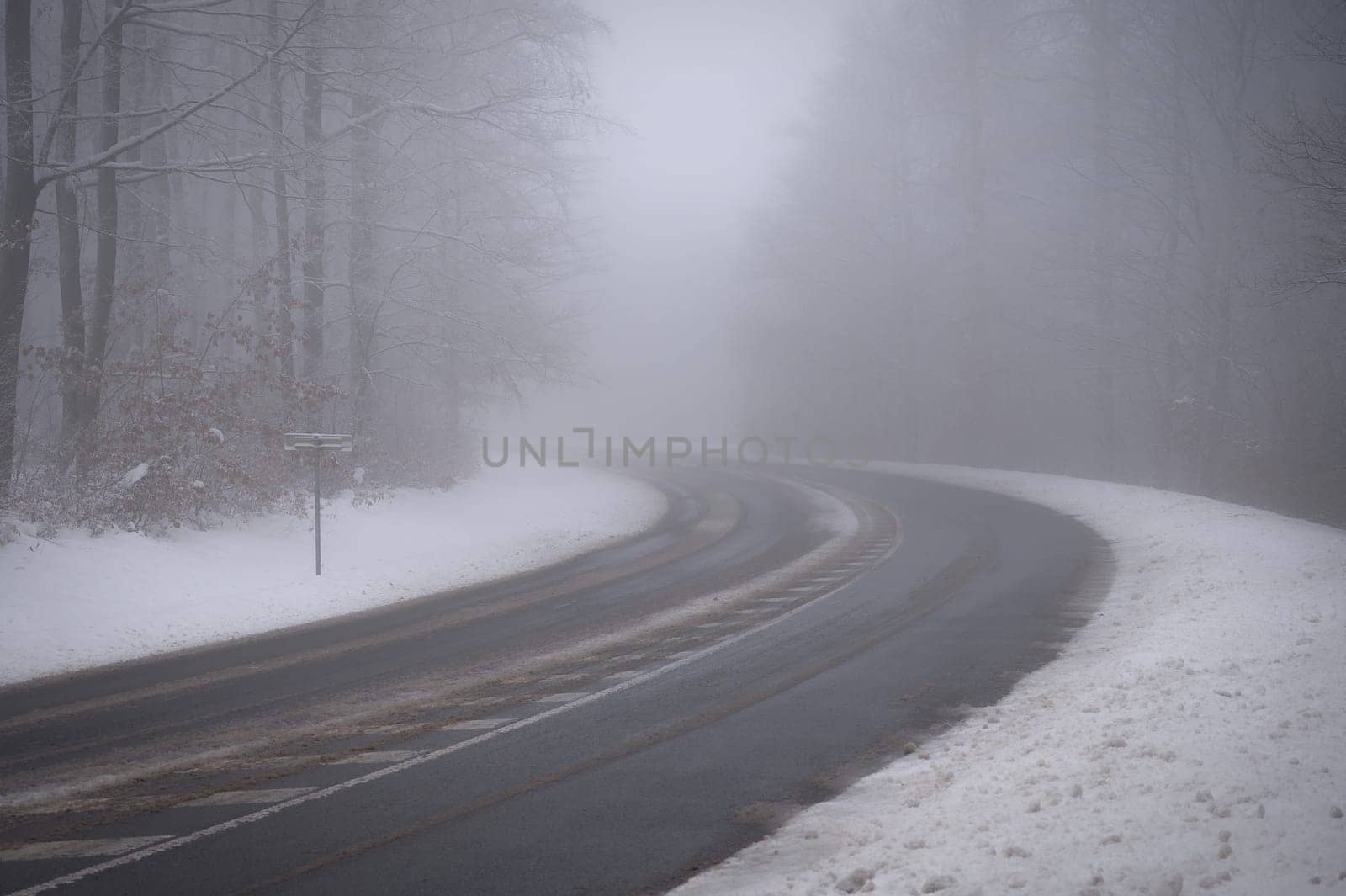 Bad weather driving - foggy hazy country road. Motorway - road traffic. Winter time. Autumn - fall.  Snow and frost on the road in winter.