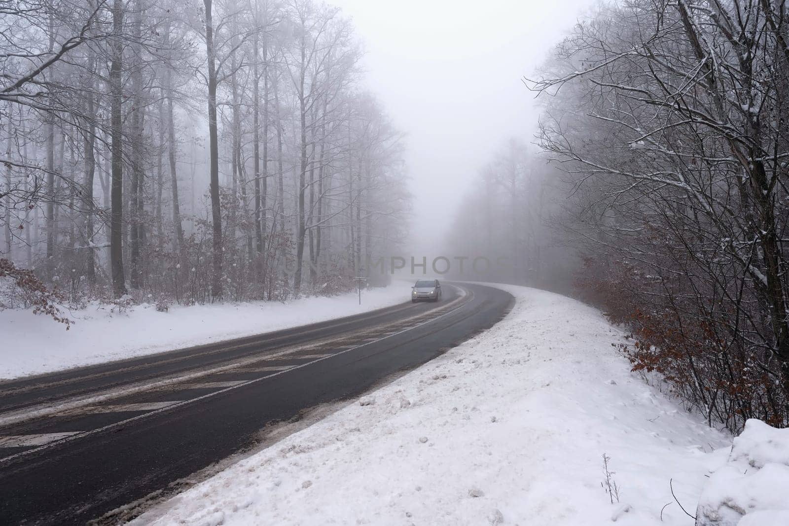 Cars in the fog. Bad winter weather and dangerous automobile traffic on the road. Light vehicles in foggy day.