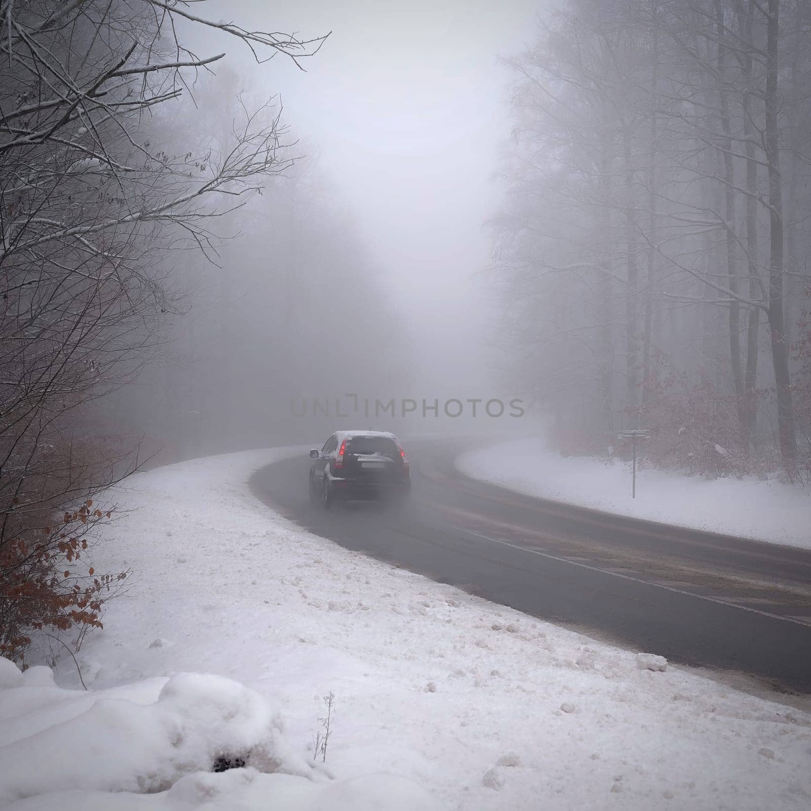 Cars in the fog. Bad winter weather and dangerous automobile traffic on the road. Light vehicles in foggy day.