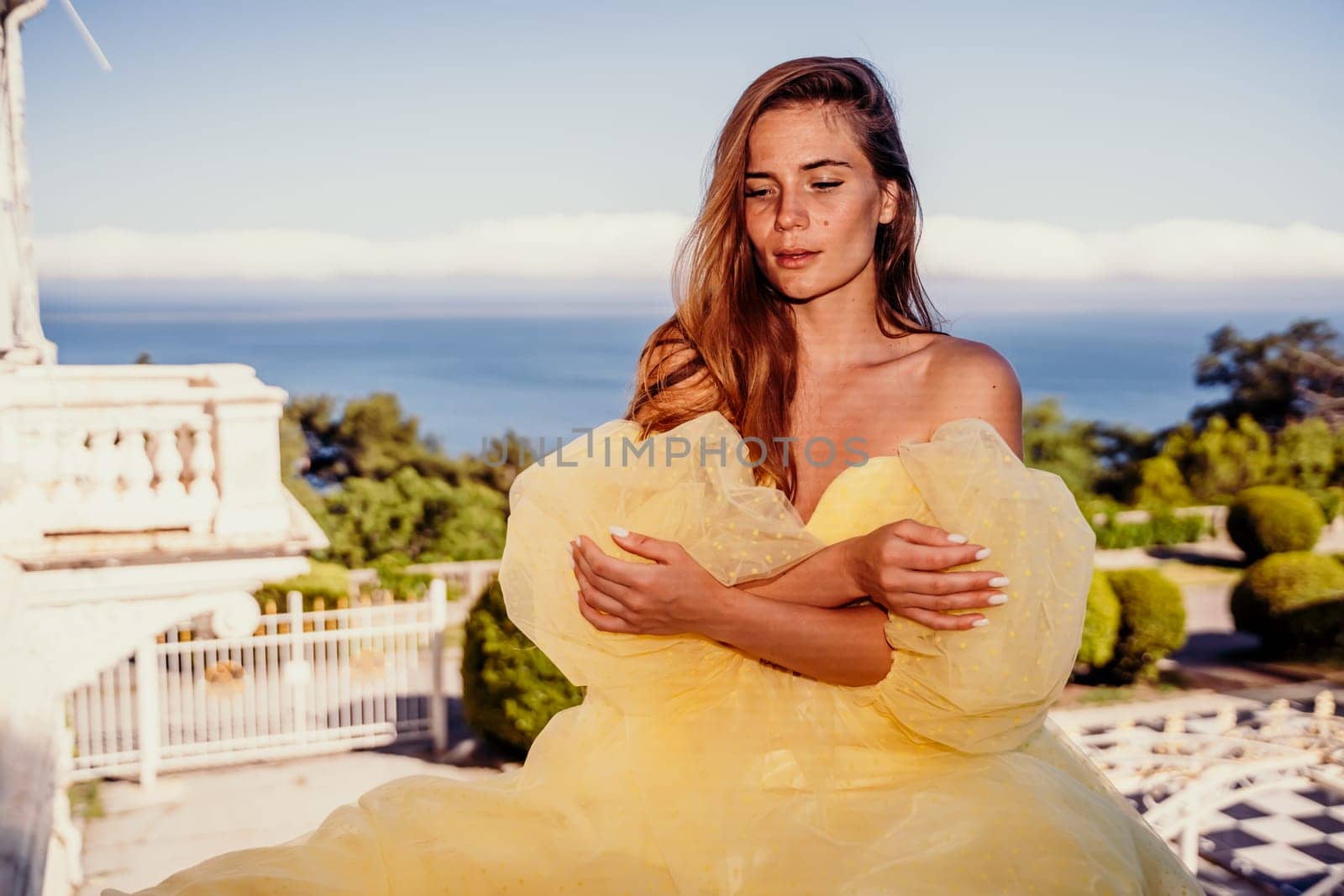 Woman yellow sea dress. Portrait of a beautiful young woman with brown hair in a gorgeous yellow dress looks into the distance