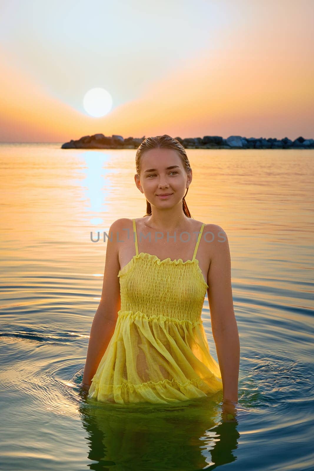 Happy young woman feeling good and relaxing at the beach at sunrise