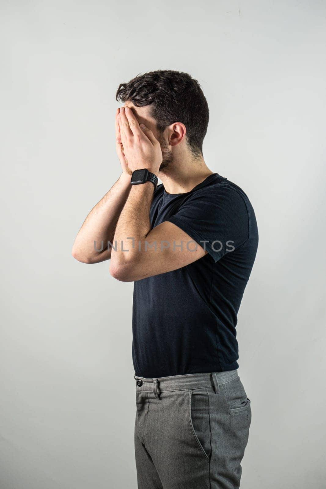 Attractive young man covering eyes with his hands by artofphoto