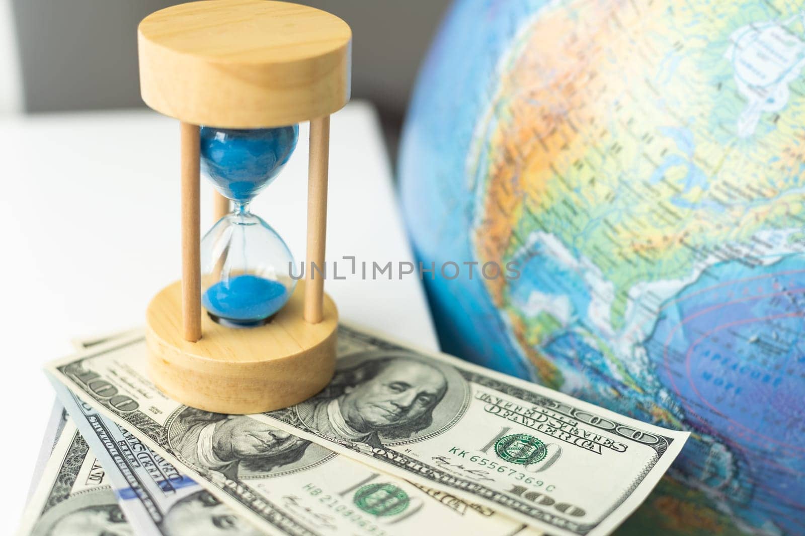 Wooden egg timer alongside a world globe or earth in a concept of running out of time to save the planet from pollution and destruction of the ecology. High quality photo