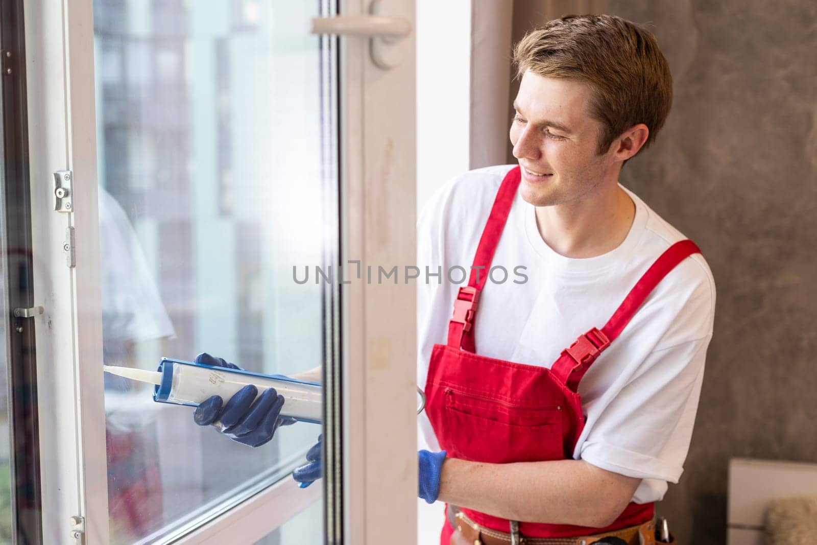 Worker installing plastic window indoors, closeup view.