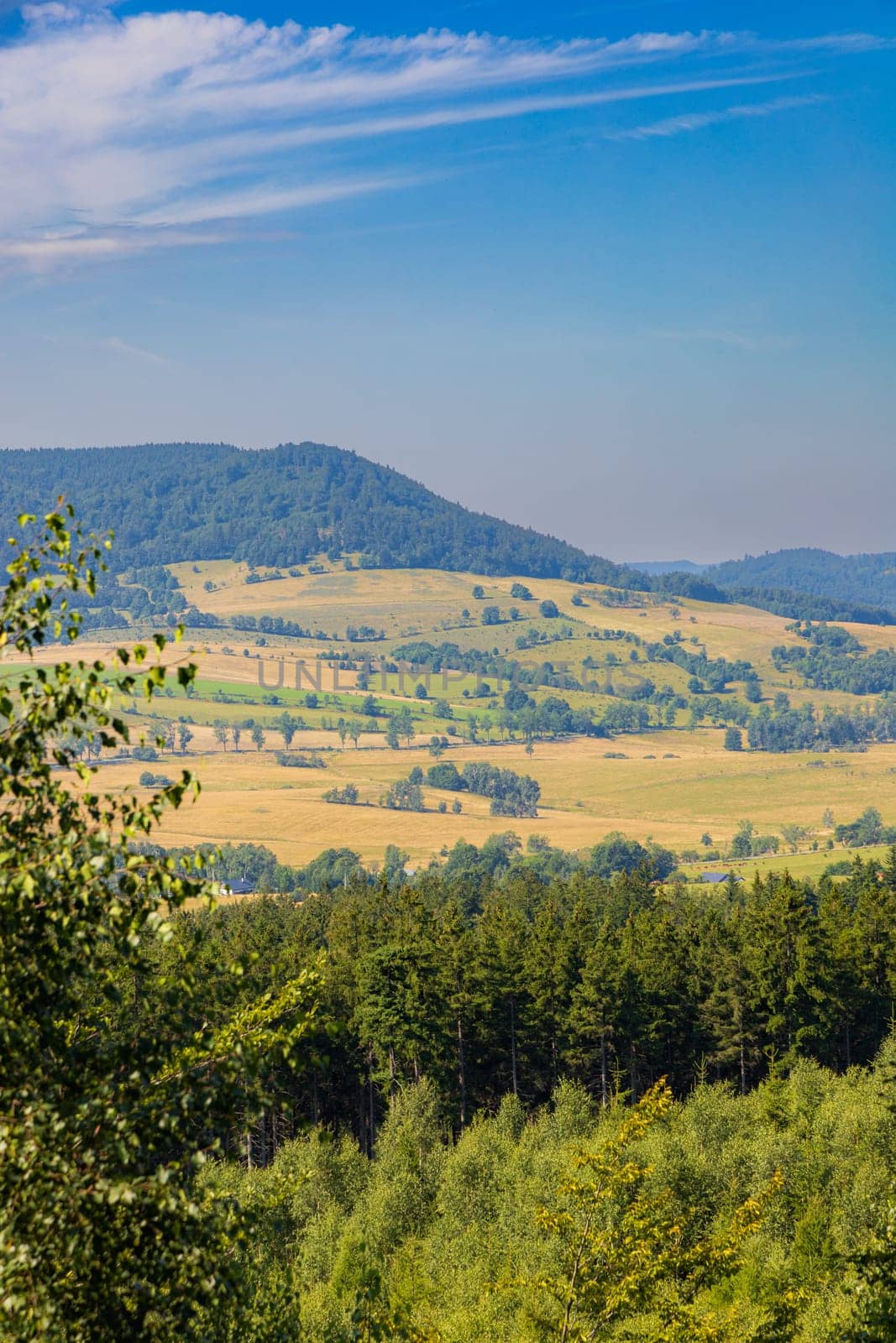 Beautiful green and blue panorama of layers of mountains and trees and some fields seen from top of viewing tower at highest mountain in this area by Wierzchu