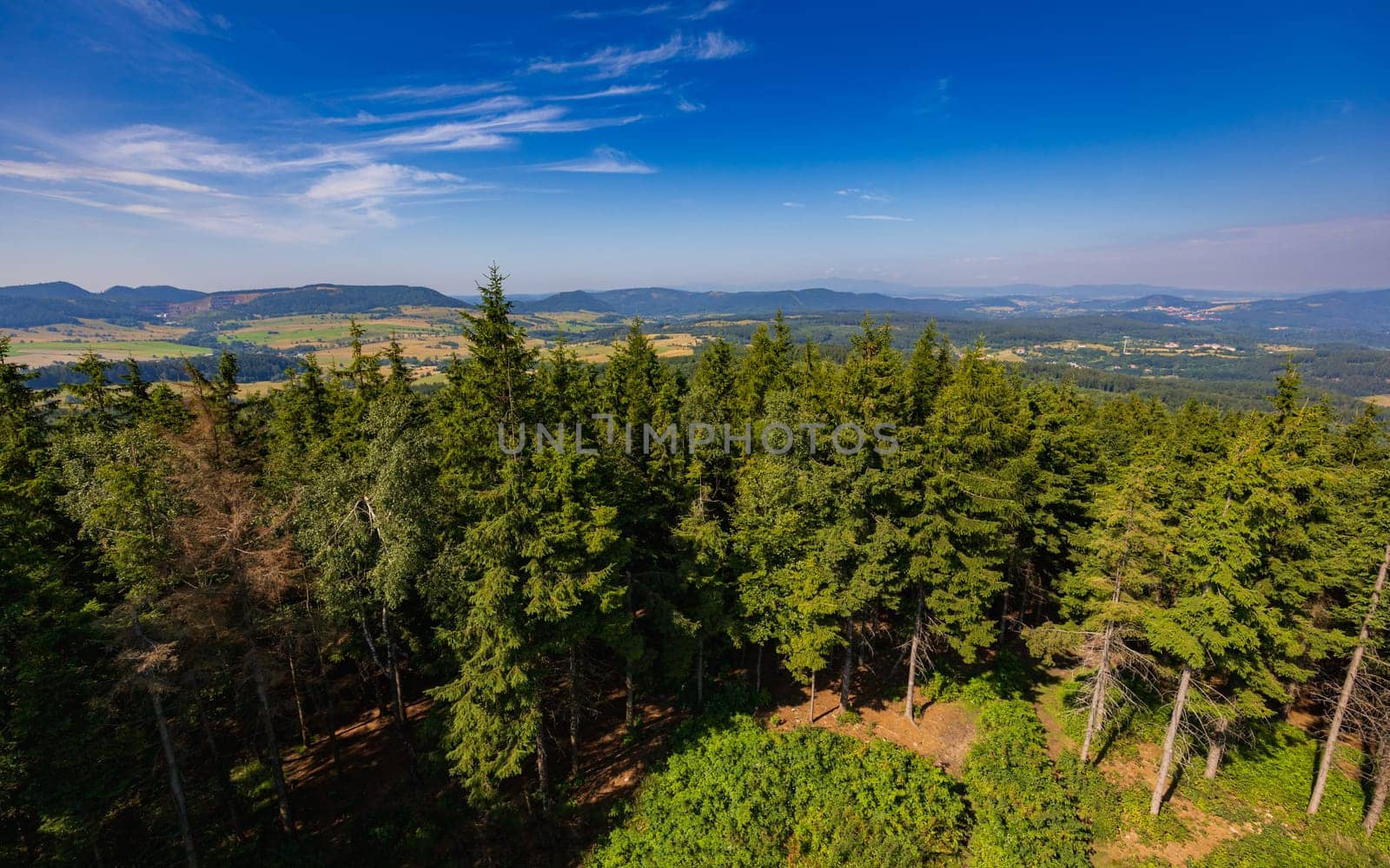 Beautiful green and blue panorama of layers of mountains and trees and some fields seen from top of viewing tower at highest mountain in this area