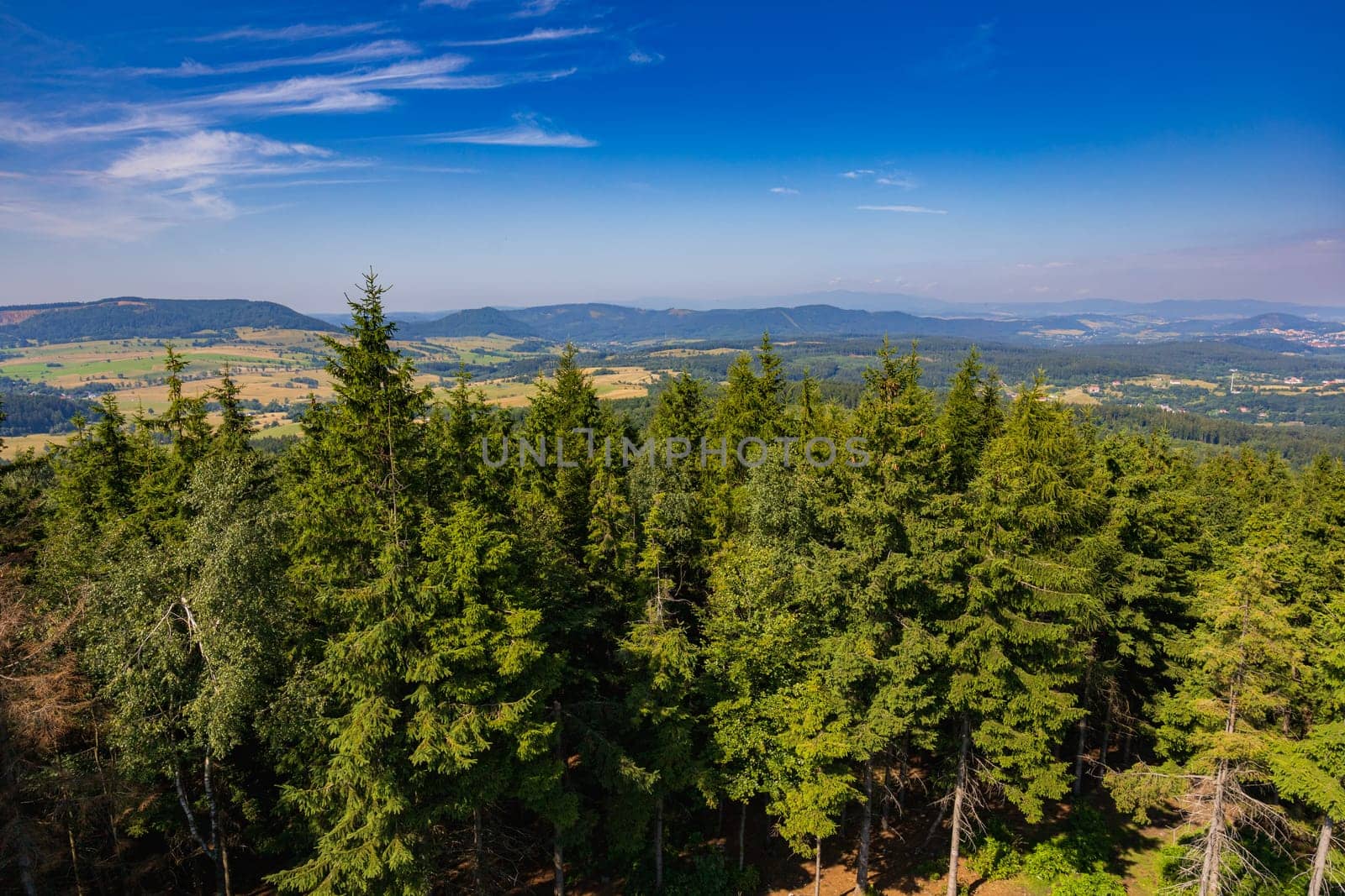 Beautiful green and blue panorama of layers of mountains and trees and some fields seen from top of viewing tower at highest mountain in this area by Wierzchu