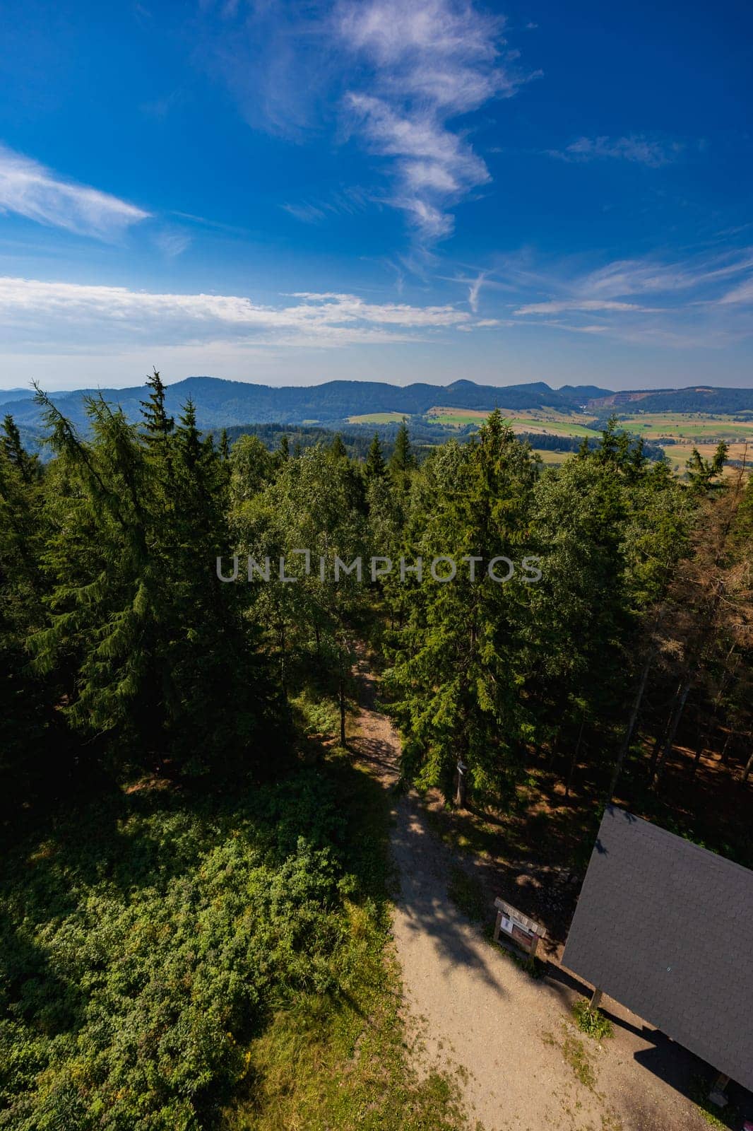Beautiful green and blue panorama of layers of mountains and trees and some fields seen from top of viewing tower at highest mountain in this area