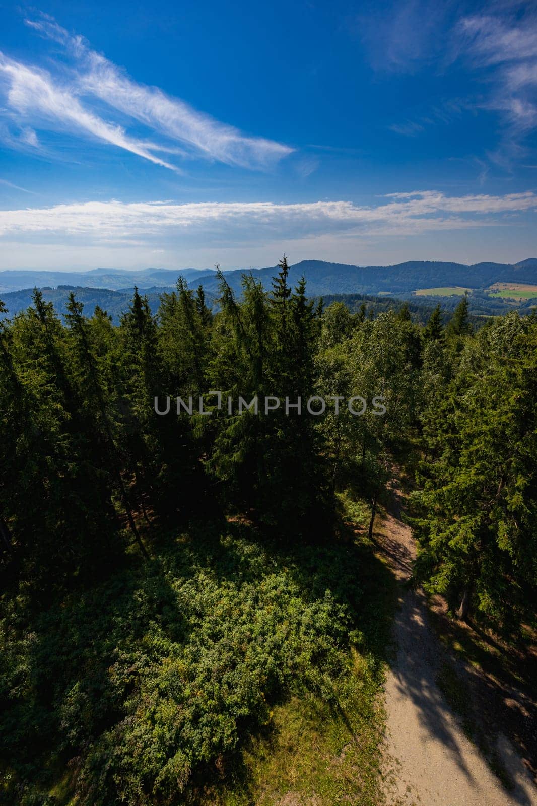 Beautiful green and blue panorama of layers of mountains and trees and some fields seen from top of viewing tower at highest mountain in this area by Wierzchu