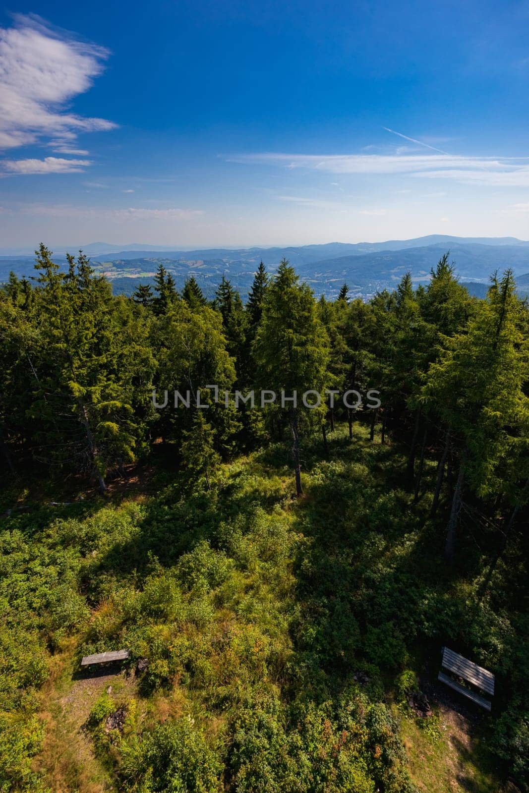 Beautiful green and blue panorama of layers of mountains and trees and some fields seen from top of viewing tower at highest mountain in this area